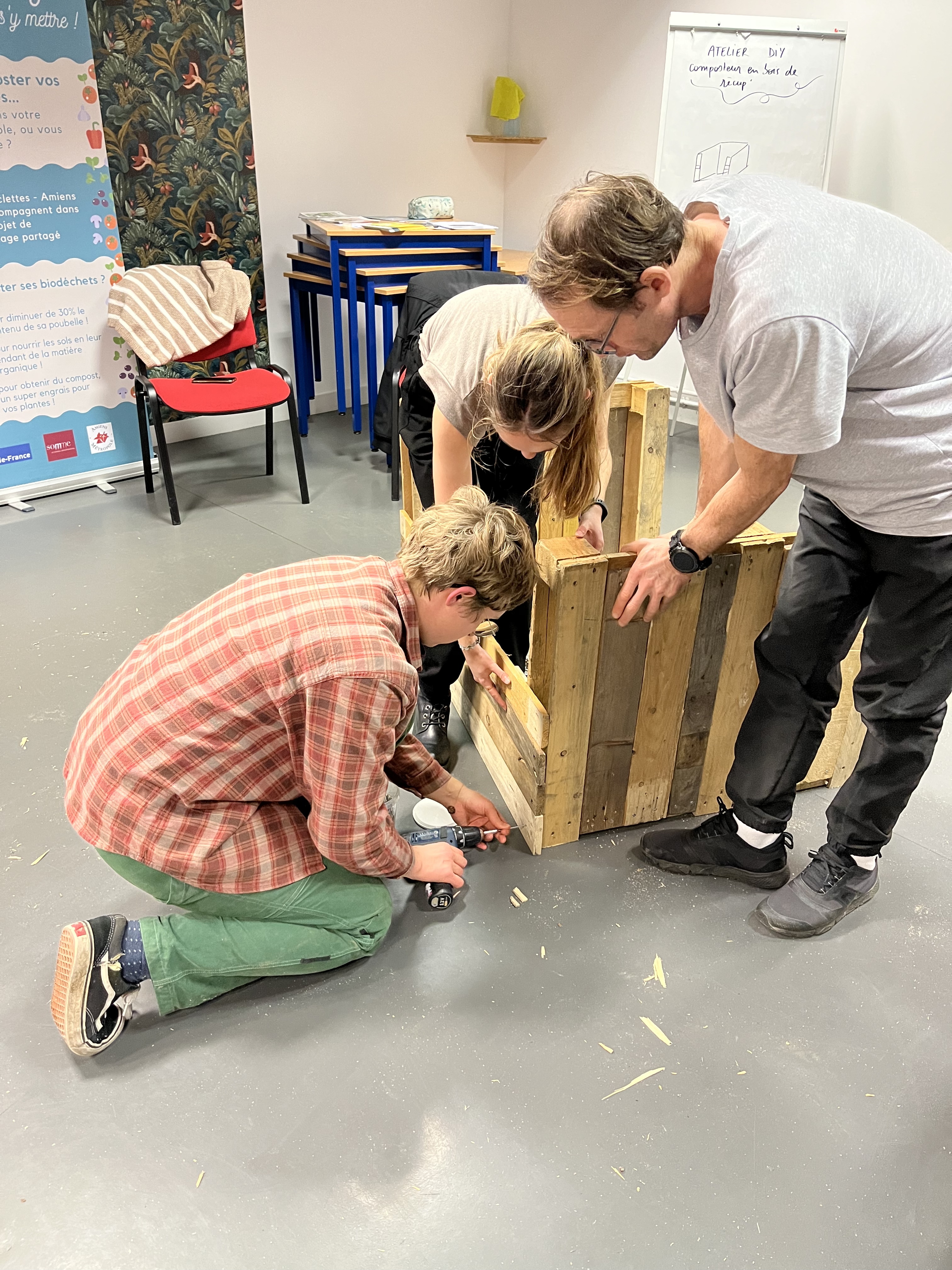 3 personnes fabriquent un composteur en bois de récupération
